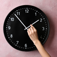 Woman changing time on big wall clock