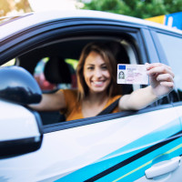 Woman with driving license. Driving school. Young beautiful woman successfully passed driving school test. Female smiling and holding driver's license.